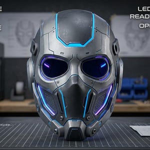 Peut inclure: Un casque de science-fiction gris métallique avec une conception monobloc, des ouvertures pour les yeux et des accents compatibles LED bleus. Le texte indique : 3D PRINTABLE STL FILE, SINGLE-PIECE DESIGN, LED COMPATIBLE, READY FOR STRAPS, OPEN EYE DESIGN.