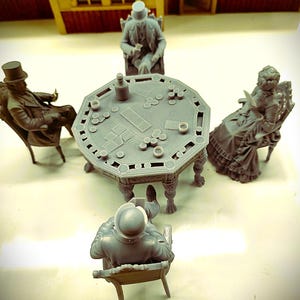 May include: A set of four grey miniature figures seated around an octagonal poker table. The figures wear period clothing, including top hats and long dresses. The table surface features molded details of cards, poker chips, and a bottle.
