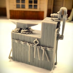 May include: A miniature gray blacksmith's workbench with an anvil, chain, and tools. The workbench has a vise and a wooden plank design. The background shows a blurred building with a window and door.