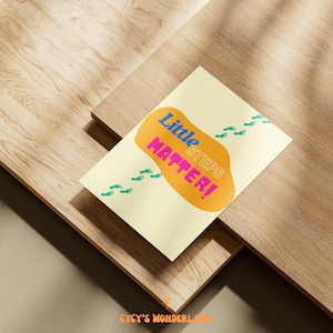 May include: A light yellow card with the text "Little Steps Matter!" in blue, pink, and orange. The card has teal footprints and is set on a wooden surface.