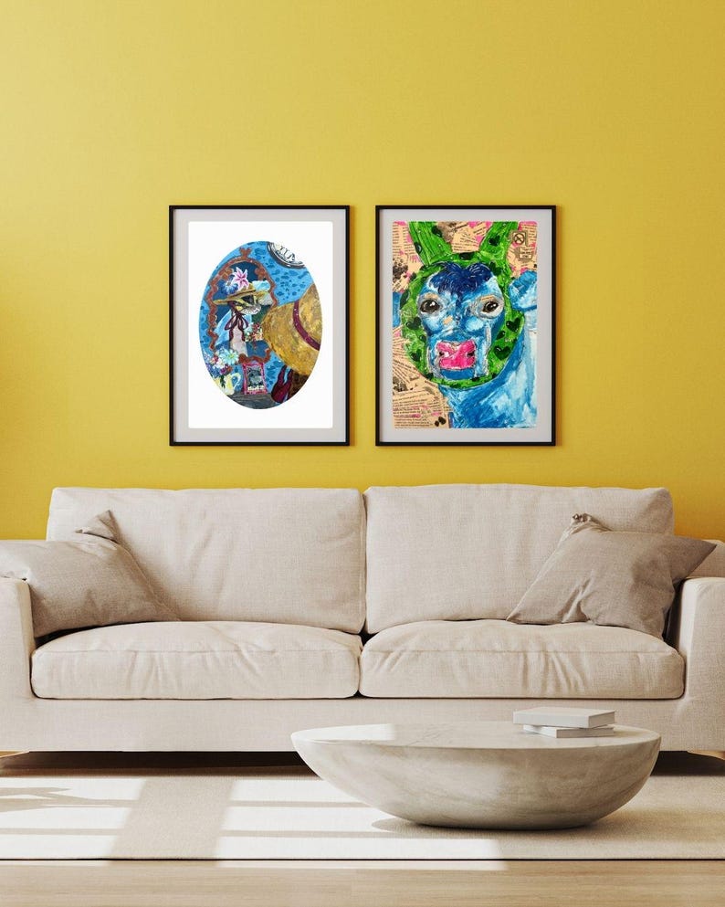 May include: Two framed abstract art prints. One features a blue and yellow oval design with floral and face elements. The other depicts a blue and green face with a green head covering and pink lips. Both are in black frames.
