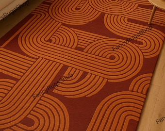 May include: A rectangular rug with a geometric pattern in shades of rust and orange. The design features curved lines and semi-circles, creating a retro, mid-century modern aesthetic. The rug is placed on a hardwood floor, suggesting a living room setting.