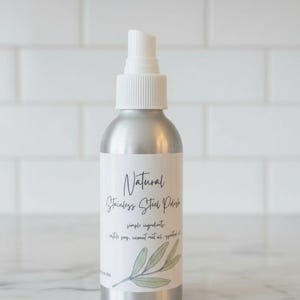 May include: A silver spray bottle of natural stainless steel polish. The label reads "Natural Stainless Steel Polish" with the words "simple ingredients" and a list of ingredients. A sprig of green leaves is at the bottom of the label.