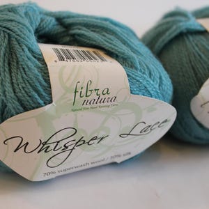 May include: Two skeins of teal blue yarn labeled "Whisper Lace" with the text "70% superwash wool / 30% silk" and "fibra natura" on the label.