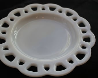 May include: A white, scalloped-edge plate with an openwork design. The plate has a smooth, glossy surface and a slightly iridescent sheen. The plate is likely made of ceramic or glass and is suitable for serving food.