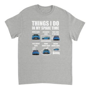 Può includere: T-shirt grigio chiaro con la scritta "THINGS I DO IN MY SPARE TIME" e illustrazioni di auto. La maglietta presenta frasi come "DRIVE CARS", "RESEARCH CARS" e "TAKE CARE OF MY CAR".