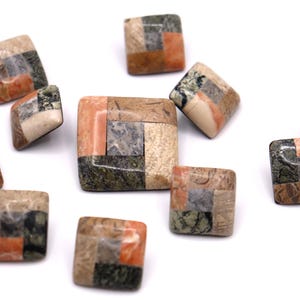 May include: A collection of square mosaic tiles in various earth tones, including orange, green, beige, and gray. The tiles are arranged in a patchwork design, creating a unique and textured appearance. Ideal for jewelry making or craft projects.
