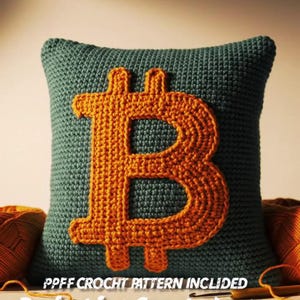 May include: A handmade, crochet pillow in teal with a large orange Bitcoin symbol. The pillow is square-shaped and features the text "BITCOIN AMIGURIMI PILLOW". The design is suitable for crypto enthusiasts and crochet fans.