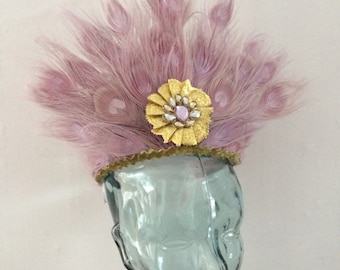 May include: A pink feather headpiece with a gold and rhinestone flower accent.