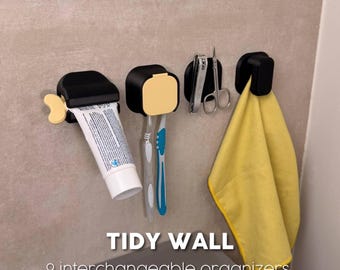 May include: Four black wall-mounted organisers with yellow accents, featuring the text TIDY WALL 9 interchangeable organisers. The units hold a tube of toothpaste, two toothbrushes, a pair of metal scissors, and a yellow cloth towel.