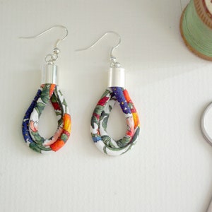 May include: Two pairs of floral fabric earrings with silver hooks. The fabric is white with orange, blue, and green floral patterns.