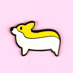 May include: A white and yellow enamel pin shaped like a cartoon corgi dog. The corgi has a black outline and black eyes.