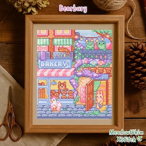 Peut inclure: Une broderie encadrée représentant une scène de boulangerie fantaisiste avec le texte "Bakery". L'œuvre présente divers bâtiments colorés, des personnages et des éléments floraux, avec le texte "Bearbury" en haut. Le cadre est de couleur marron clair.