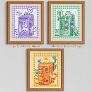 Puede incluir: Tres obras de arte en punto de cruz enmarcadas. La parte superior izquierda presenta una caja de jugo morada con fantasmas y la palabra "Spooky". La parte superior derecha muestra una caja de jugo verde con ranas y la palabra "Mandrake". La obra de arte inferior representa una caja de jugo de calabaza con patitos y la palabra "Pumpkin".