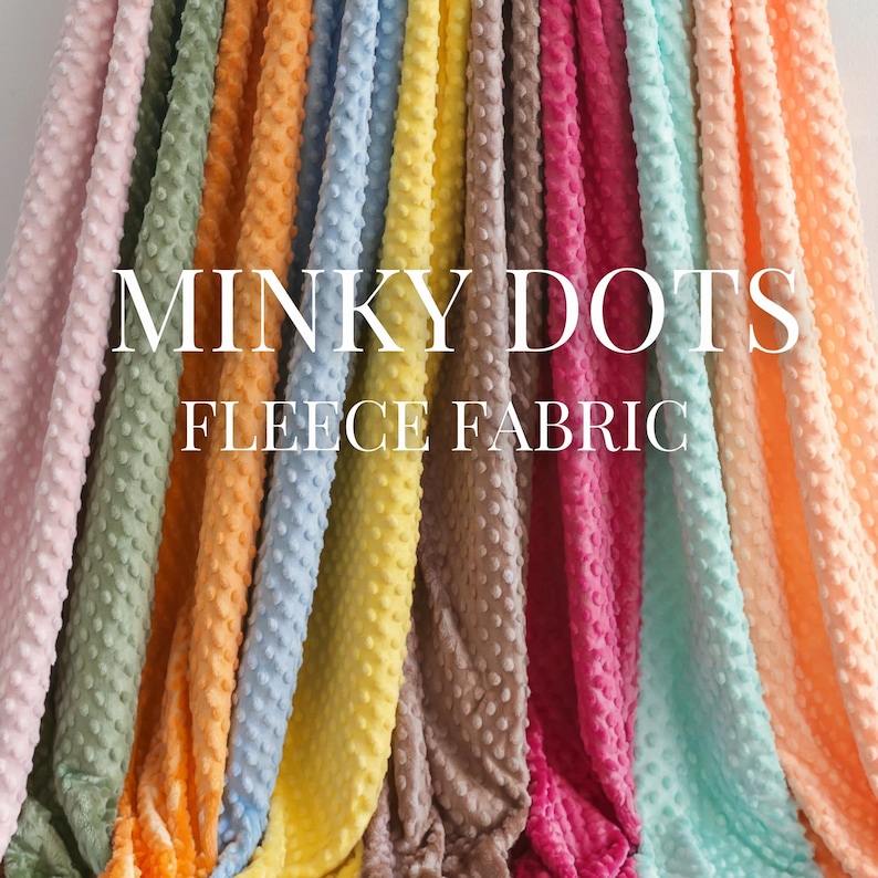 May include: A selection of Minky Dots fleece fabric in a range of colours, such as pink, green, orange, blue, yellow, brown, red, and teal. The fabric has a textured, dotted surface. The words "Minky Dots Fleece Fabric" are displayed in white.