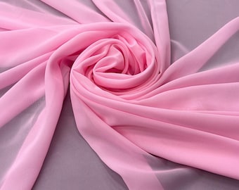 May include: A close-up of a swirl of pink fabric. The fabric is a light, sheer material, with a smooth texture. The fabric is arranged in a spiral, with the center of the spiral being the darkest pink. The background is a muted gray.