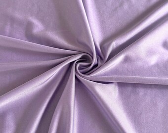 May include: A close-up shot of a lavender fabric with a silky sheen. The fabric is gathered and folded, creating soft shadows and highlights. The material appears smooth and drapes gracefully, suggesting a lightweight textile.