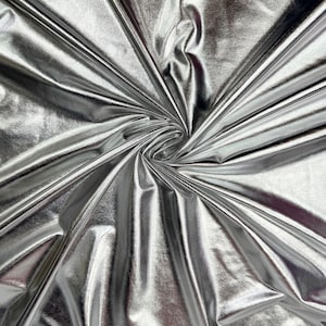 May include: A close-up shot of a shiny, silver fabric with a metallic sheen. The fabric is gathered and swirled, creating a dynamic pattern of light and shadow. The material appears to be smooth and reflective, suitable for apparel or decorative projects.
