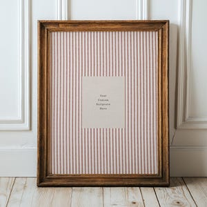 May include: A rectangular wooden picture frame with a striped pink and white background. The frame has a light brown finish and features the text "Your Custom Scripture Here" on a beige rectangle.