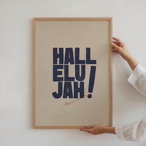 Może przedstawiać: Oprawiony plakat z napisem "Hallelujah" w kolorze granatowym na beżowym tle. U dołu napis "Praise the Lord" pisany kursywą. Rama wykonana jest z jasnego drewna.