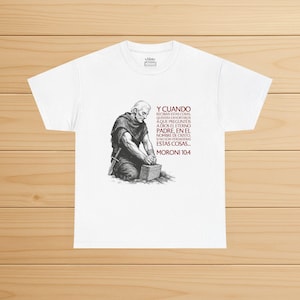 May include: White t-shirt featuring a black and white illustration of a man kneeling and working on a stone block. The shirt includes red text in Spanish, with the text "Y CUANDO... MORONI 10:4".