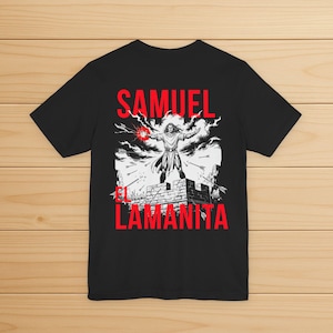 Puede incluir: Camiseta negra con un gráfico de una figura con los brazos extendidos, relámpagos y el texto rojo "SAMUEL LAMANITA". La ilustración es en blanco y negro, con una pared de piedra al fondo.