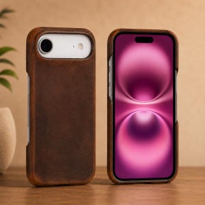 May include: A dark brown phone case with a smooth, matte texture shown from both the front and back. The back view reveals a cutout for the camera lens and flash, while the front view displays a smartphone with a vibrant pink screen display.