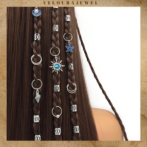 May include: Braided brown hair decorated with silver hair cuffs and charms. Charms include a seashell, sunburst, and starfish. The image has the text "VELOURAJEWEL" at the top.