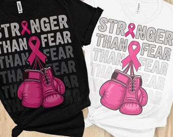 May include: Black and white t-shirts with the text "STRONGER THAN FEAR" and a pink ribbon and boxing gloves graphic. The design features a pink ribbon and a pair of pink boxing gloves.