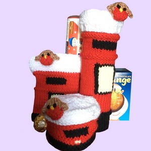 Può includere: Contenitori regalo a forma di cassetta postale rossa e nera lavorati a mano, con finiture bianche e un piccolo pettirosso in cima. All'interno dei contenitori sono visibili una scatola di biscotti e una barretta di cioccolato.