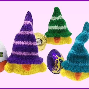 May include: Hand-knitted Easter gnome egg covers in purple, green, and teal. Each gnome has a yellow body and a pointed hat with stripes or a solid colour. Chocolate eggs are partially visible.