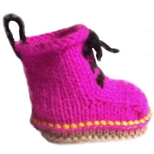 Może przedstawiać: Ręcznie robiony, dziergany but w żywym kolorze fuksji. But ma czarną pętlę u góry i czarne sznurowadła. Podeszwa jest w kolorze jasnobrązowym, z żółtymi przeszyciami. Unikalny, ręcznie robiony przedmiot, inspirowany butami roboczymi.