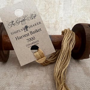 May include: A spool of tan embroidery floss labeled "Simply Shaker Harvest Basket 7000 Colorfast" by The Gentle Art.