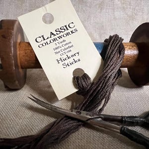 May include: A spool of brown embroidery floss with a tag that reads "CLASSIC COLORWORKS 5 Yards 100% Cotton Not Colorfast CCT-166 Hickory Sticks".
