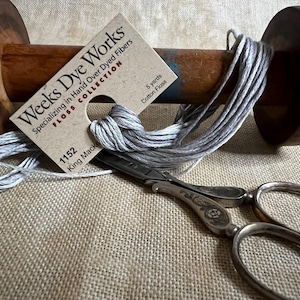 May include: A spool of gray hand-dyed cotton floss with a Weeks Dye Works label. The label reads "Weeks Dye Works, Floss Collection, Specializing in Hand Over Dyed Fibers, 1152 King Macke, 5 yards Cotton Floss".