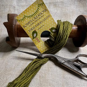 May include: A spool of green embroidery floss with a label that reads "Romy's Creations Colors and Threads Three Fairies Green" and a pair of antique scissors.