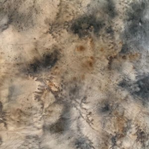 May include: A textile surface featuring a tie-dye pattern with blended shades of charcoal gray, muted beige, and soft brown. The fabric displays organic, branching ink-like bleeds and mottled textures that create a layered, abstract appearance.