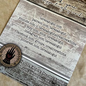 May include: A thank you card with a rustic woodgrain background. The card features the text "thank you for supporting my work" and a list of social media handles and websites for Teresa Kogut's Creative Whims. The card also includes the text "Teresa Kogut's Creative Whims Otisville Michigan, USA".