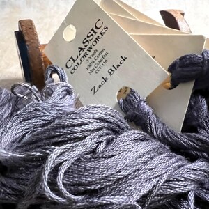 May include: A skein of gray embroidery floss with a label that reads "CLASSIC COLOR WORKS 5 Yards 100% Cotton Not Colorfast CCT-110 Zack Black".