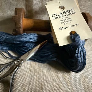 May include: A spool of blue embroidery floss with a label that reads "Classic Colorworks, 5 Yards, 100% Cotton, Not Colorfast, CCT-218, Blue Corn".