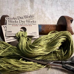 May include: A skein of green cotton floss with two cards labeled "Weeks Dye Works" and "2205 Grasshopper" with a wooden spool and a pair of scissors.