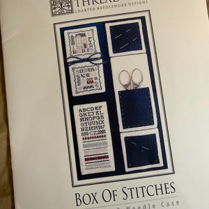 May include: A pattern booklet titled The Drawn Thread Box Of Stitches Scissors & Needle Case. The cover features cross-stitch designs on white fabric with blue accents, including an alphabet, the word NEEDLES, and a pair of silver scissors.