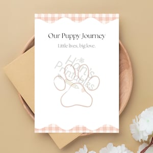 Puede incluir: Una tarjeta blanca con el texto "Our Puppy Journey" y "Little lives, big love." presenta una ilustración de huella de pata. La tarjeta tiene un borde de cuadros rosas y blancos y está sobre un plato de madera con un sobre beige.