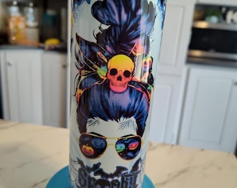 May include: A tall, cylindrical tumbler with a spooky Halloween design. The tumbler features a woman's face with sunglasses reflecting jack-o'-lanterns and a skull in her hair. The words "Spooky Mama" are printed on the front. The background is light blue with dark blue and purple accents.