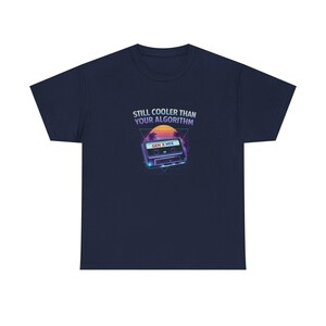 Puede incluir: Camiseta azul marino con un gráfico retro de una cinta de cassette y el texto "STILL COOLER THAN YOUR ALGORITHM" y "GEN X MIX". El diseño presenta un atardecer y formas geométricas.