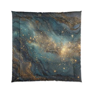 May include: A comforter with a celestial design. The comforter features a swirling pattern of teal, navy, and gold, resembling a galaxy. The design includes gold flecks and streaks, creating a starry effect. The comforter is square and has a soft, quilted appearance.