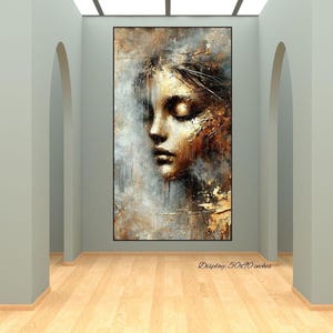 Könnte beinhalten: Abstrakte Porträtmalerei eines Frauengesichts mit geschlossenen Augen. Das Kunstwerk zeigt eine Palette aus Gold-, Braun- und Grautönen mit strukturierten Pinselstrichen. Das Gemälde wird in einem schwarzen Rahmen präsentiert. Anzeige: 127x178 cm.