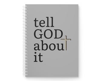 Op de afbeelding: Een spiraalgebonden notitieboek met een grijze kaft. De kaft toont de tekst "tell GOD about it" in een vetgedrukte, zwarte letter, met een goudkleurig kruis. Het notitieboek is ontworpen om in te schrijven en aantekeningen te maken.