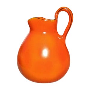May include: A vibrant orange glass pitcher with a rounded body and a curved handle. The pitcher has a glossy finish and a slightly flared rim. The handle is a loop shape, and the pitcher is set against a white background.