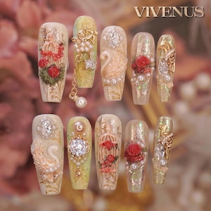 May include: A set of ten artificial nails with ornate designs. Each nail features a different design, including pearls, gems, roses, and gold accents. The nails are in various shades of beige, gold, and pink, with the word "VIVENUS" in gold at the top.